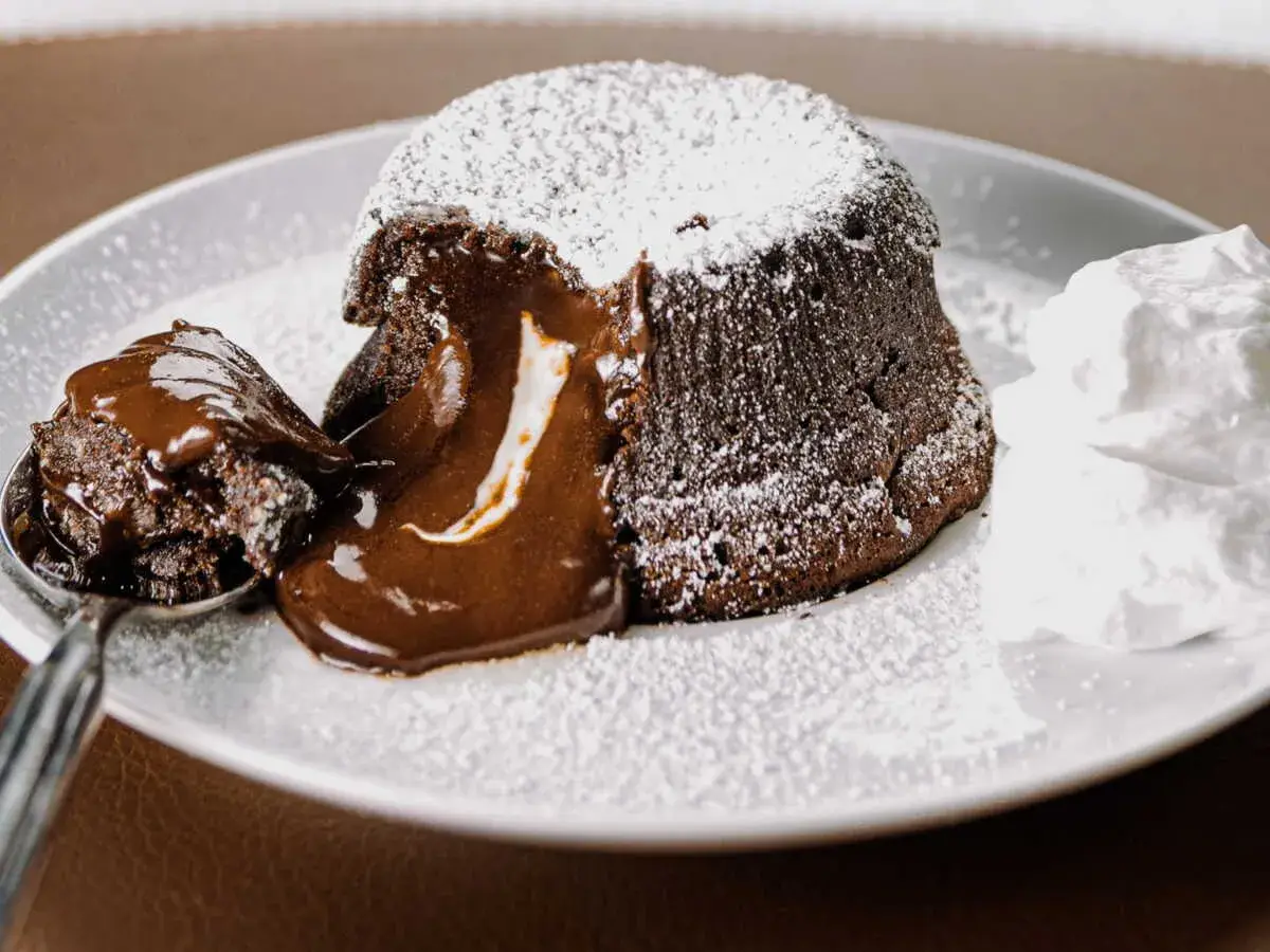 Un fondant au chocolat dégoulinant, saupoudré de sucre glace, avec une cuillère de gâteau et de la crème fouettée. Un dessert rapide dernière minute parfait !
