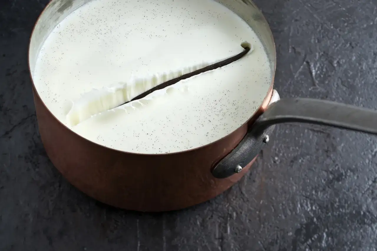 Une gousse de vanille infuse dans une préparation crémeuse, prélude à une délicieuse crème anglaise.