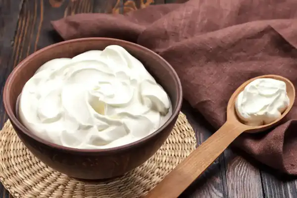 Un bol de crème onctueuse, parfaite pour une crème diplomate, avec une cuillère en bois remplie de cette douceur.