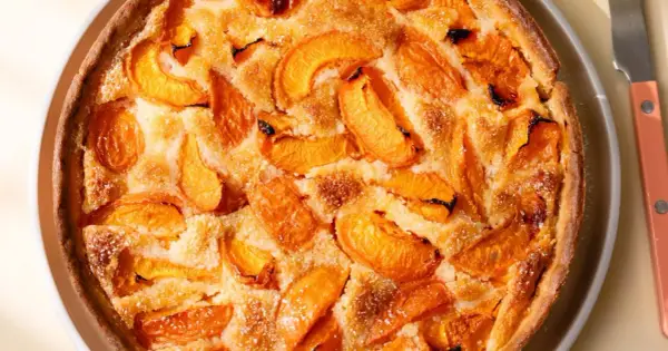 Tarte abricot amande dorée, garnie de fruits juteux et saupoudrée de sucre glace. Un délice gourmand.