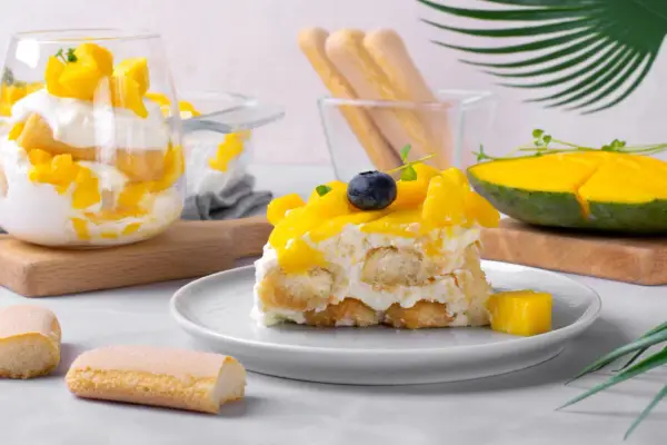 Un délicieux tiramisu mangue, garni de fruits frais et de biscuits à la cuillère. Une touche tropicale pour un dessert rafraîchissant.