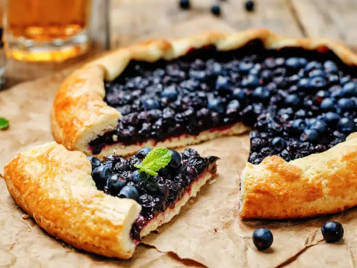 Une délicieuse tarte aux myrtilles, avec une croûte dorée et une garniture généreuse de fruits bleus, prête à être dégustée.