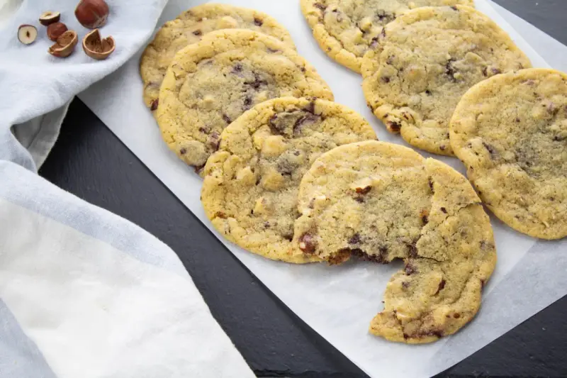 Gros plan sur des cookies aux pépites de chocolat et noisettes, dont le beurre fondu a donné une texture parfaite. Un délice !